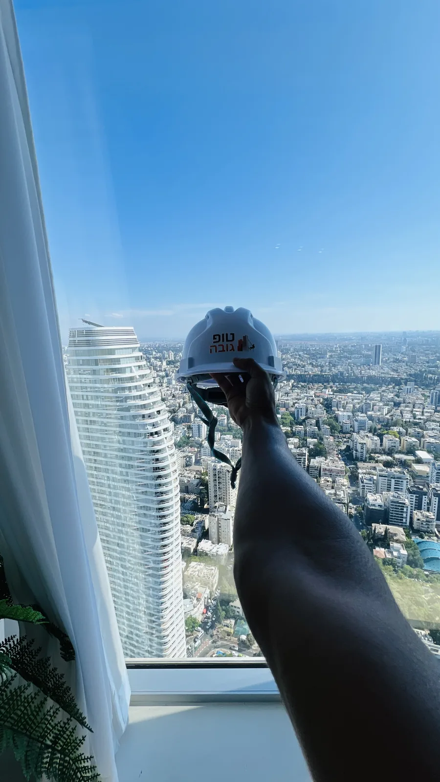 Safety helmet held over the Tel Aviv skyline